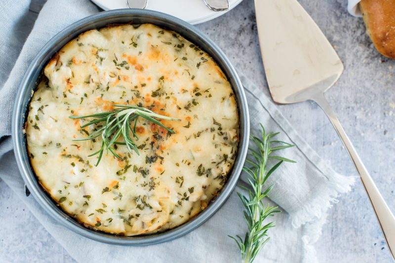 overhead of rosemary alfredo lasagna in a round springform cake pan