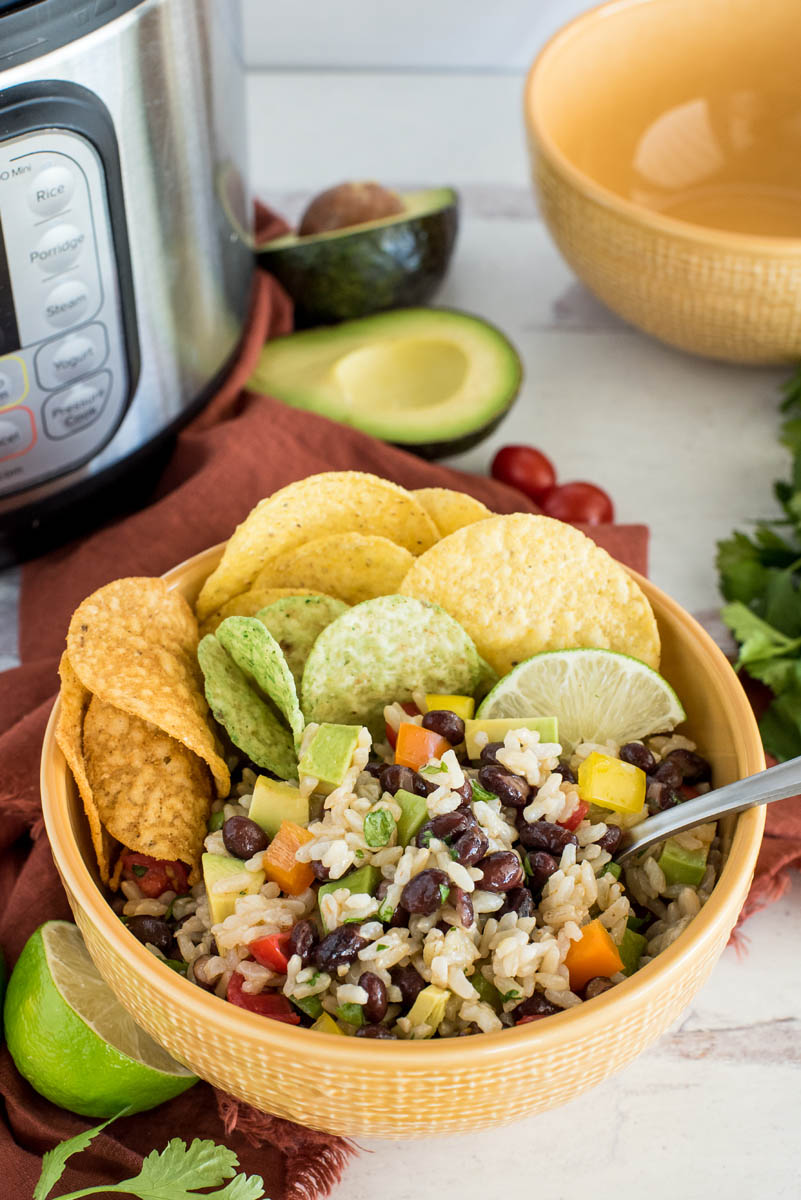 bowl of black bean and rice salad with vegetables in front of an instant pot