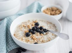 pressure cooker steel cut oats with fresh blueberries in a white cereal bowl with a teal checkered napkin