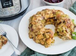 Thanksgiving stuffing made in the electric pressure cooker. A close up of a ring of stuffing with an instant pot and cranberries in the background