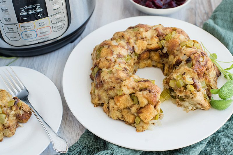 Thanksgiving stuffing made in the electric pressure cooker. A close up of a ring of stuffing with an instant pot and cranberries in the background