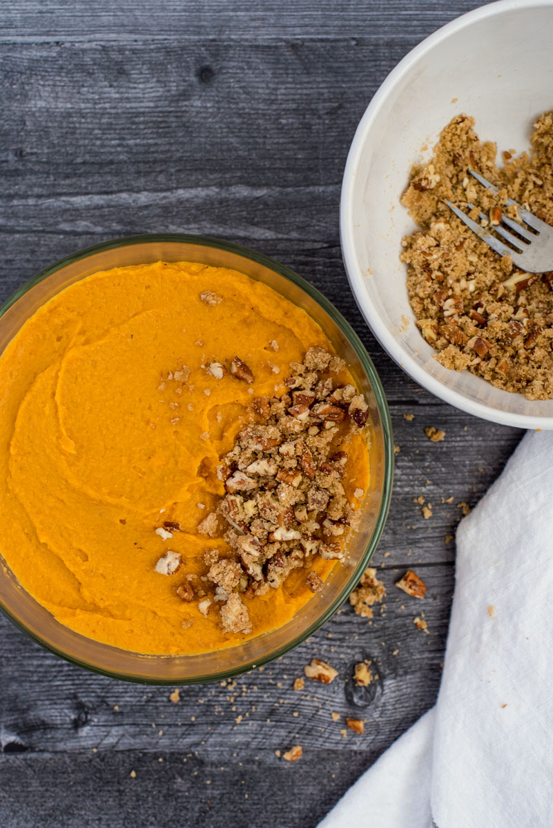 covering a cooked sweet potato casserole with crumble toping