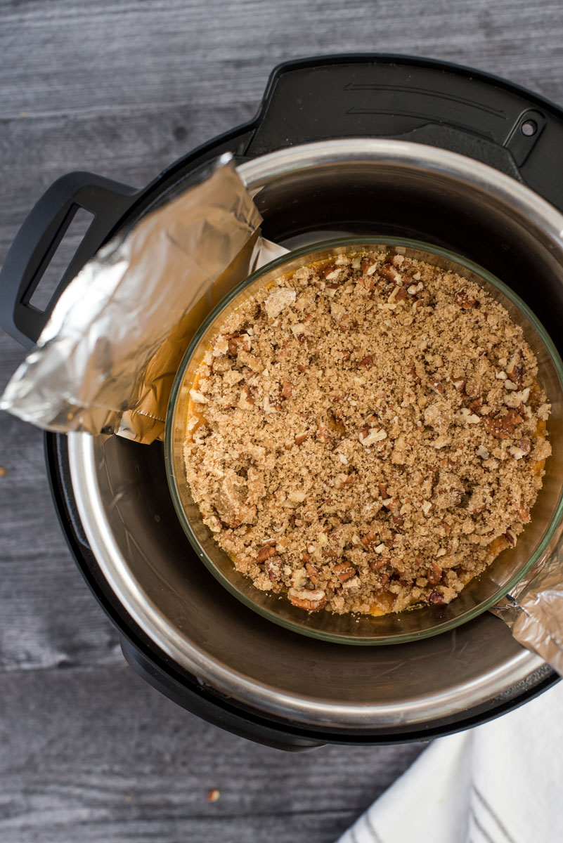 placing an uncooked sweet otato casserole into a ressure cooker with a foil sling