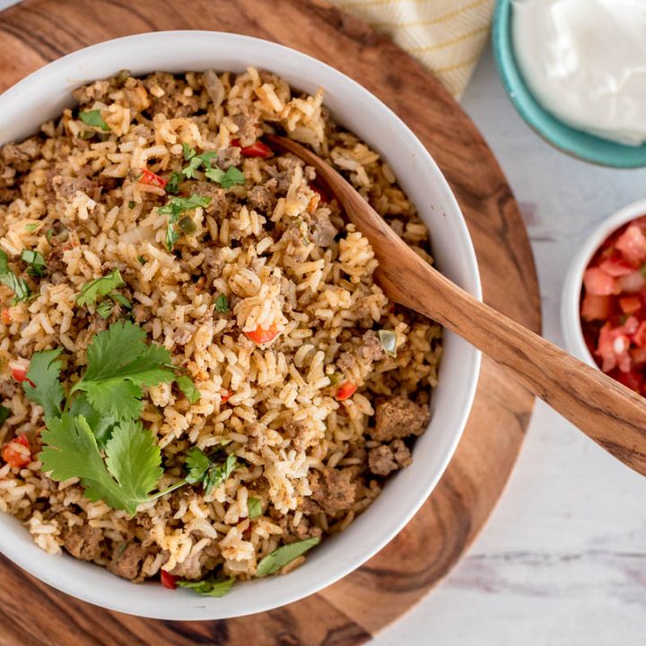 overhead of a white bowl with Instant Pot taco rice and a wooden spoon