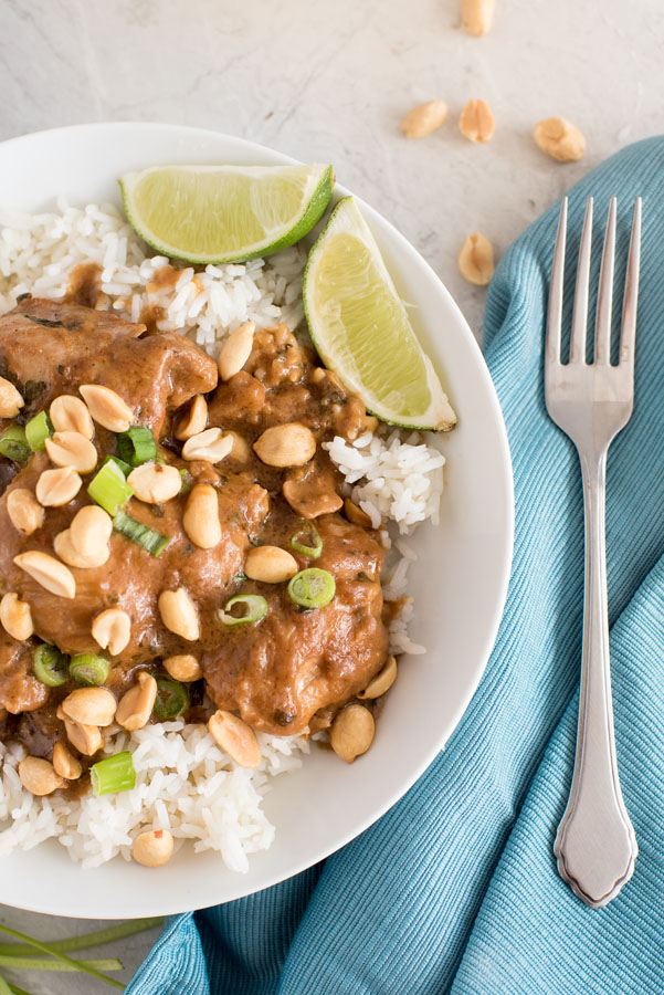 Instant Pot thai peanut chicken thighs with white rice, crunchy peanuts and lime wedges