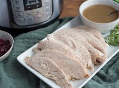 A rectangle plate of Pressure Cooker Thanksgiving Turkey recipe, with and Instant Pot, gravy, and cranberries in the background