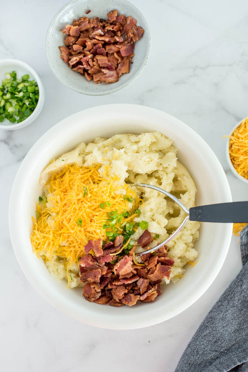 mixing the filling for twice baked ranch potatoes in a white bowl