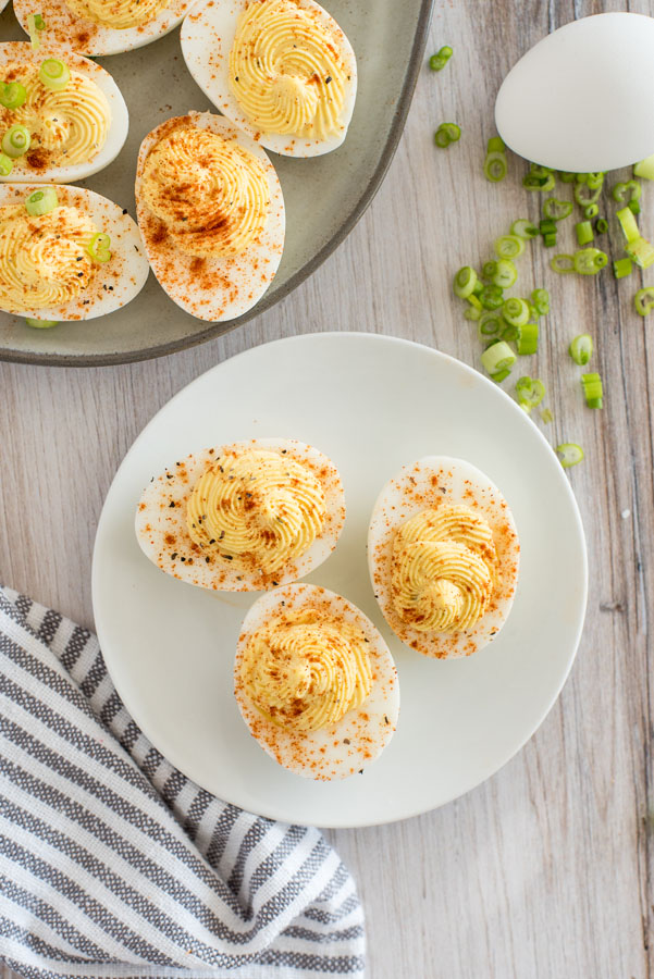 Overhead of a small white plate with three Instant Pot deviled eggs filled with homemade deviled egg filling with smoked paprika.