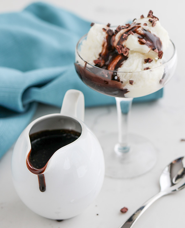 45 degree shot included in the Instantly Sweet Dessert Cookbook - featuring a small white picture with a drip of dark chocolate sauce running down the side, with a scoop of ice cream in a shallow stemmed glass, topped with more chocolate sauce