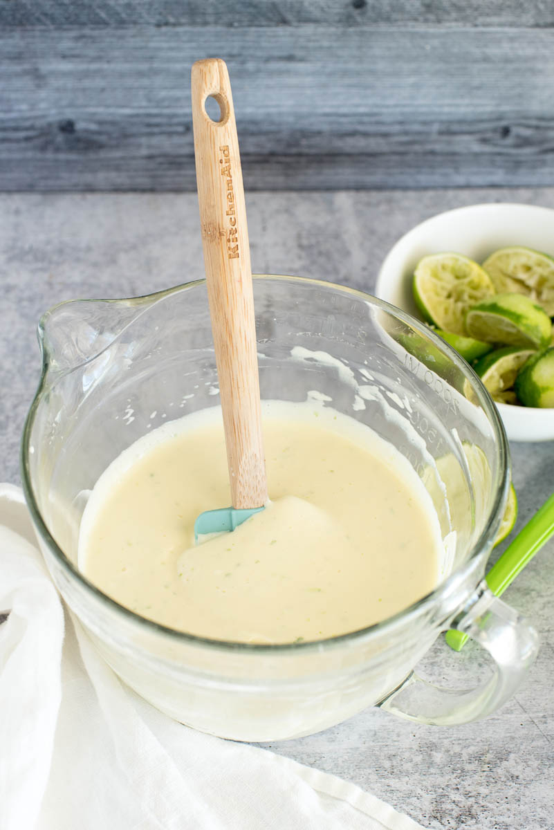 mixing the filling for instant pot key lime pie in a glass mixing bowl