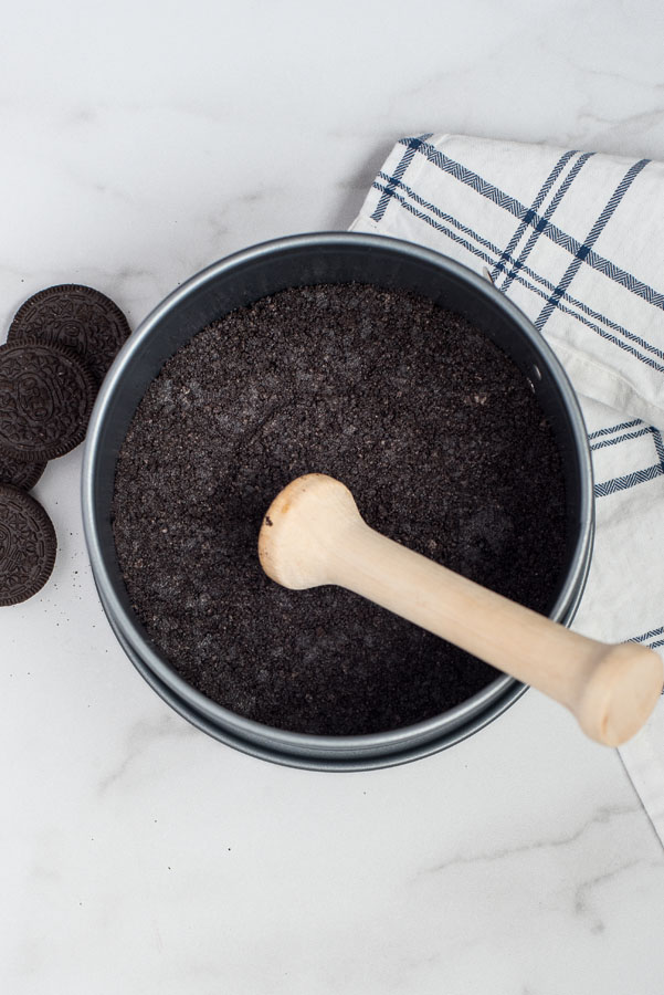 Using a tamper to press the Oreo crust for a strawberry cheesecake recipe.