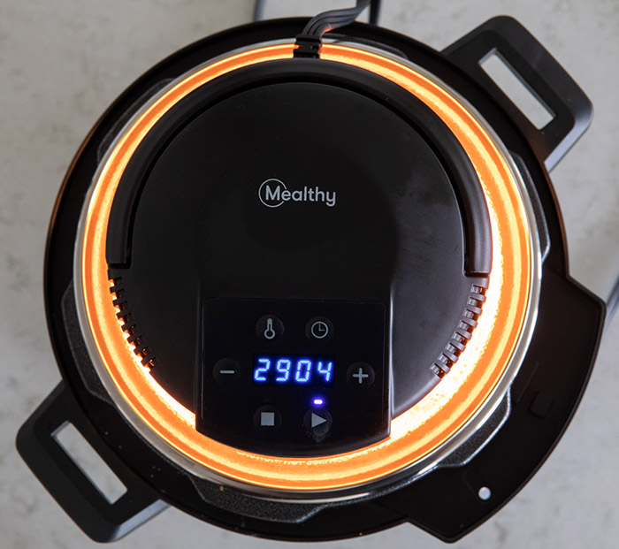 overhead shot of the Mealthy CrispLid in use. with a glowing orange light from the heating element visable.