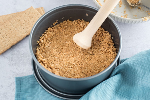 Tamping the graham cracker crust in a spring form pan for an Instant Pot cheesecake.