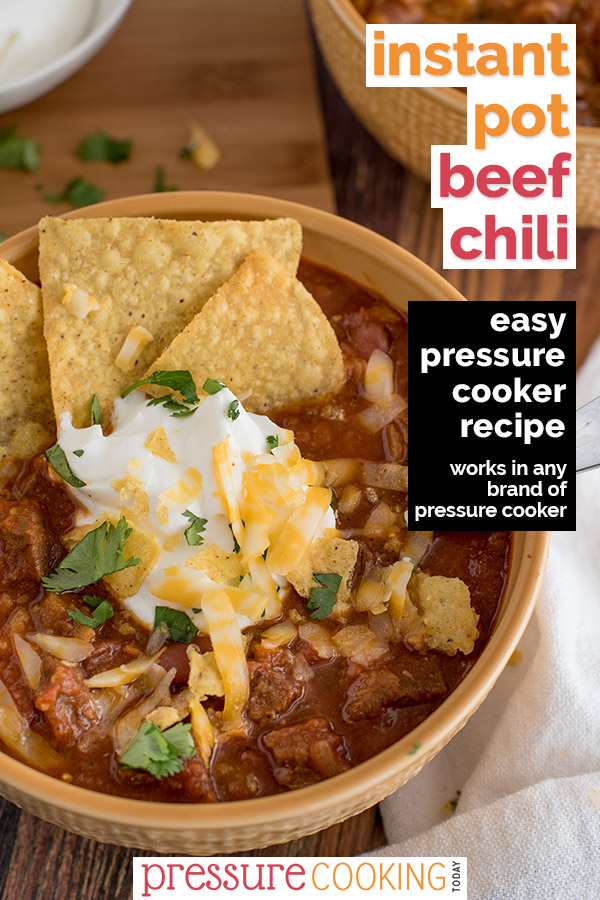 Pin It Now: Instant Pot Beef Chili, dished up in a yellow serving bowl, topped with tortilla chips, sour cream, cheddar cheese, and cilantro