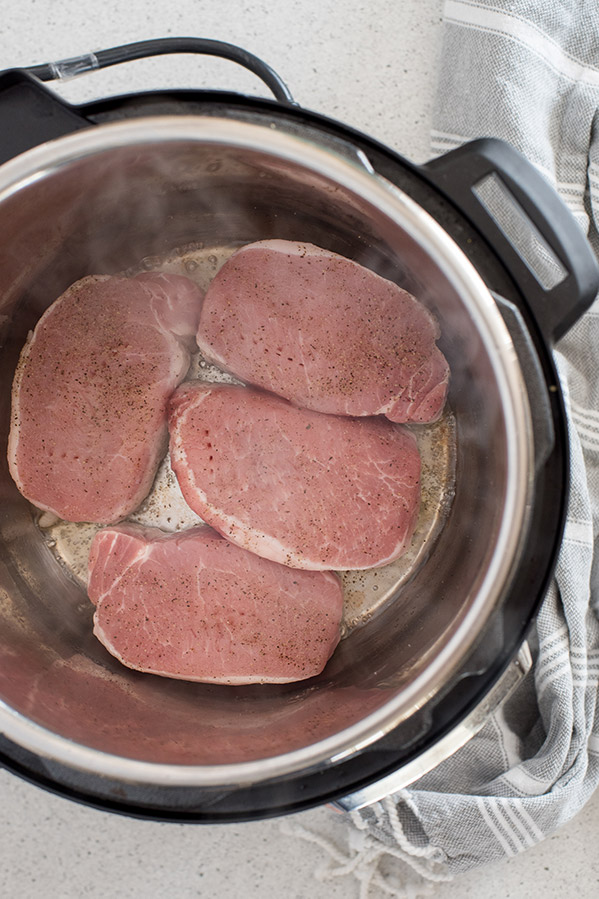 Boneless Pork Chops sauteing inside of the Instant Pot cooking pot