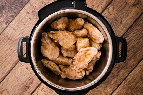 Instant Pot Teriyaki chicken wings after sauteeing but before pressure cooking stacked inside an Instant Pot