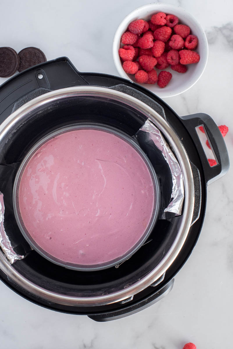 An overhead shot of the purple-red raspberry cheesecake on a foil sling inside the Instant Pot