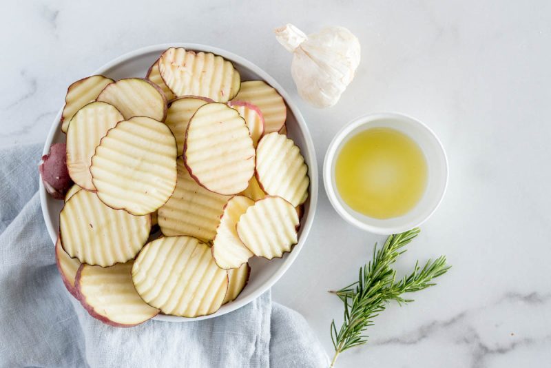 an overhead shot of scallop cut new potatoes with rosemary, garlic, and oil