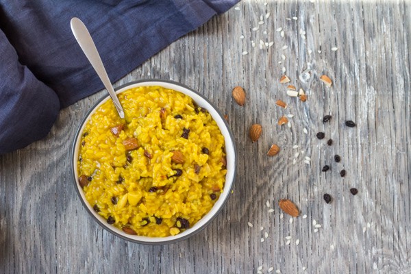 Instant Pot Saffron Risotto with Almonds and Currants in a white bowl with spoon