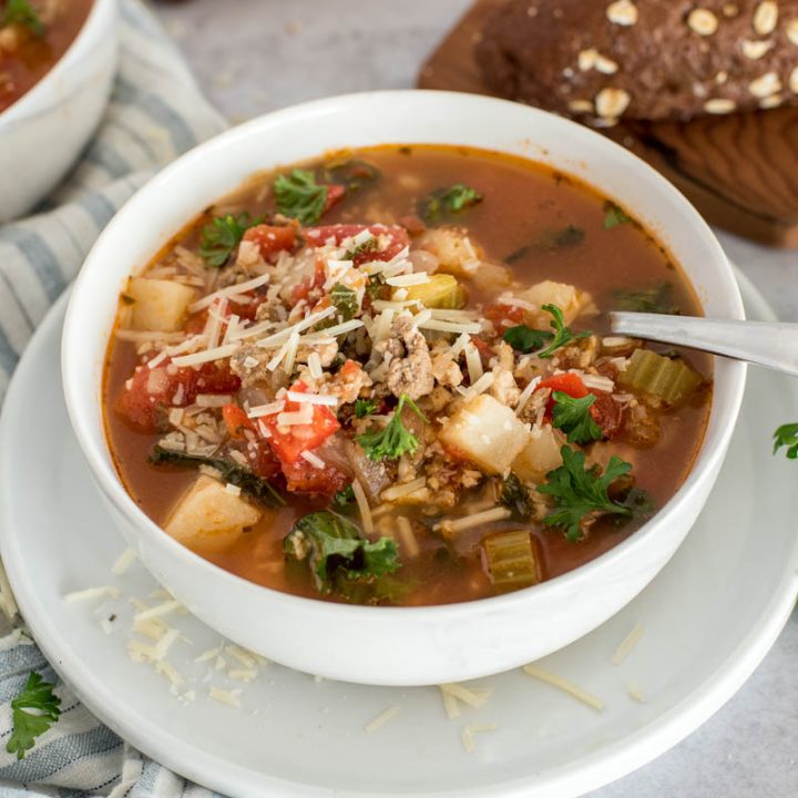 white bowl of tomato sausage soup with cheese