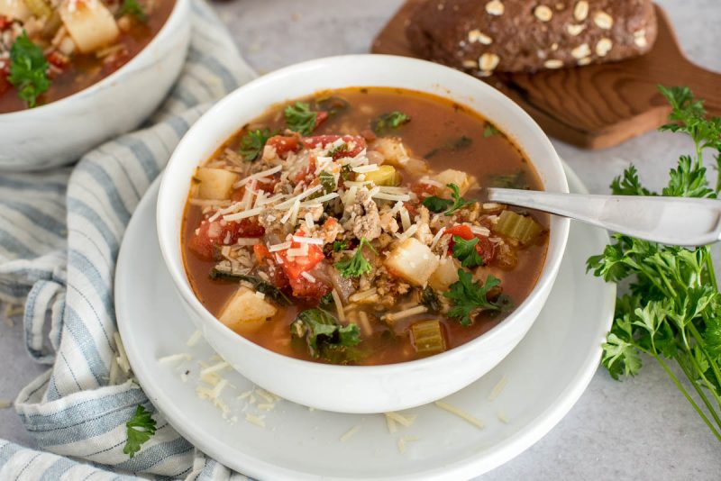 white bowl of tomato sausage soup with cheese