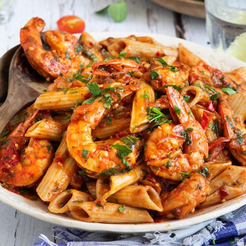 Close up on a large white serving plate of pressure cooker / Instant Pot Shrimp Fra Diavlo over penne pasta topped with fresh parsley.