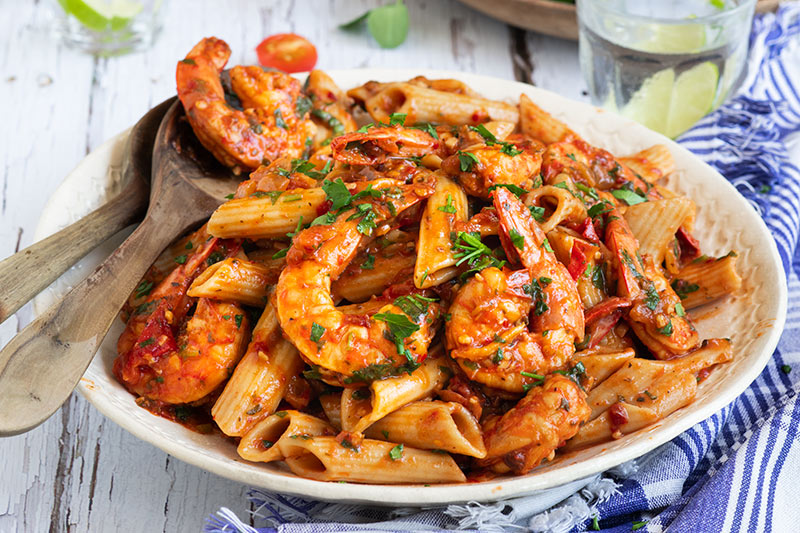 Close up on a large white serving plate of pressure cooker / Instant Pot Shrimp Fra Diavlo over penne pasta topped with fresh parsley.