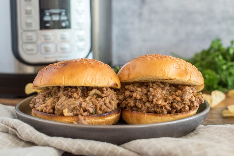 Close up picture of two sloppy joes made with cajun chicken soup, served on buns and placed in front of an Instant Pot.