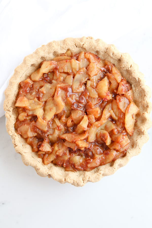 overhead shot of Instant Pot Caramel Apple Pie from Tidbits, included in the Instantly Sweet Dessert Cookbook - featuring a pie crust holding soft apples in a cinnamon sauce in a simple pie crust