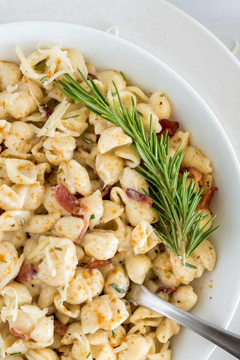 close up on mac and cheese with a sprig of fresh rosemary