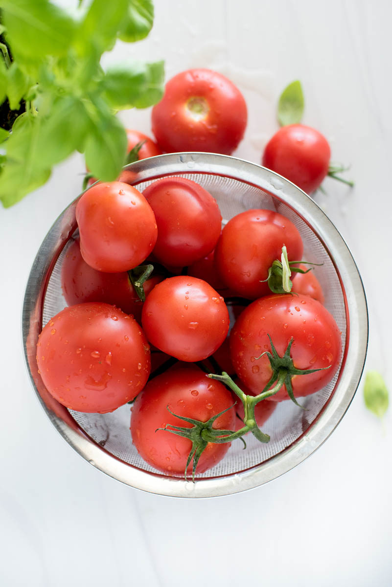 an overhead shot of a collander full of fresh garden tomatoes