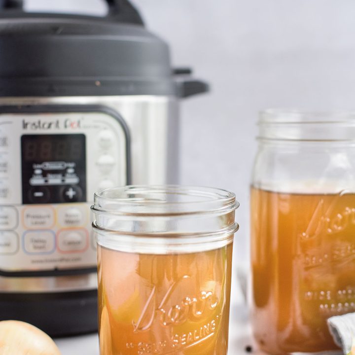 a head-on shot of Instant Pot vegetable stock in a mason jar in front of an Instant Pot