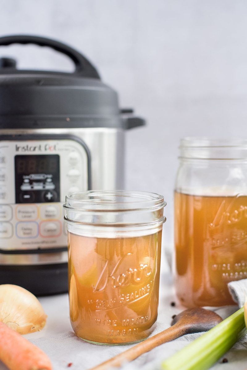 a head-on shot of Instant Pot vegetable stock in a mason jar in front of an Instant Pot